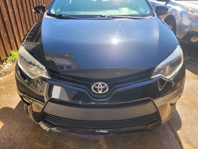 Blue Toyota sedan front view with shiny grille and headlights