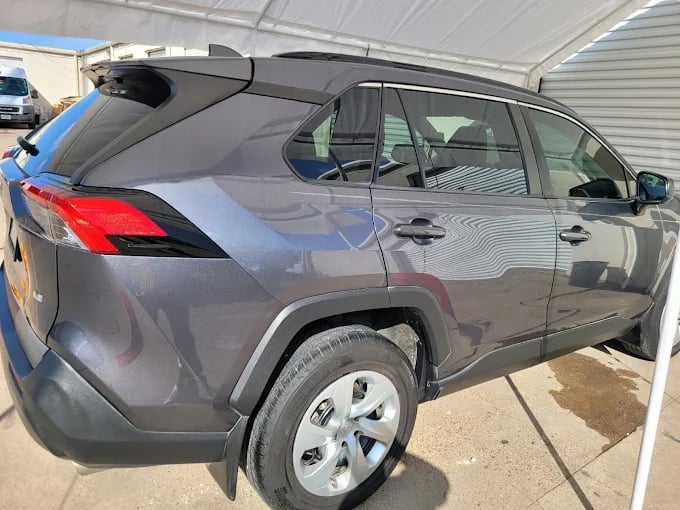 Gray Toyota RAV4 SUV parked under a white canopy with reflective surfaces