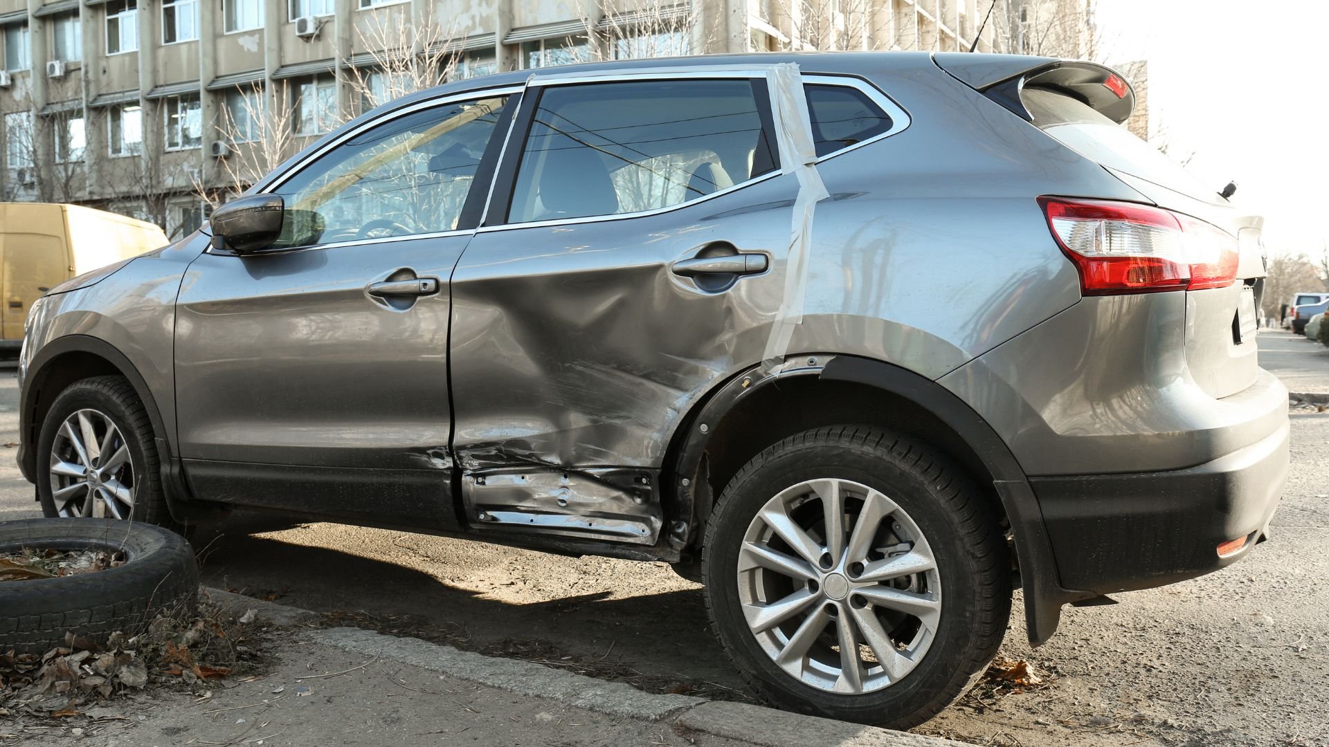 Gray SUV with severe side damage parked on urban street