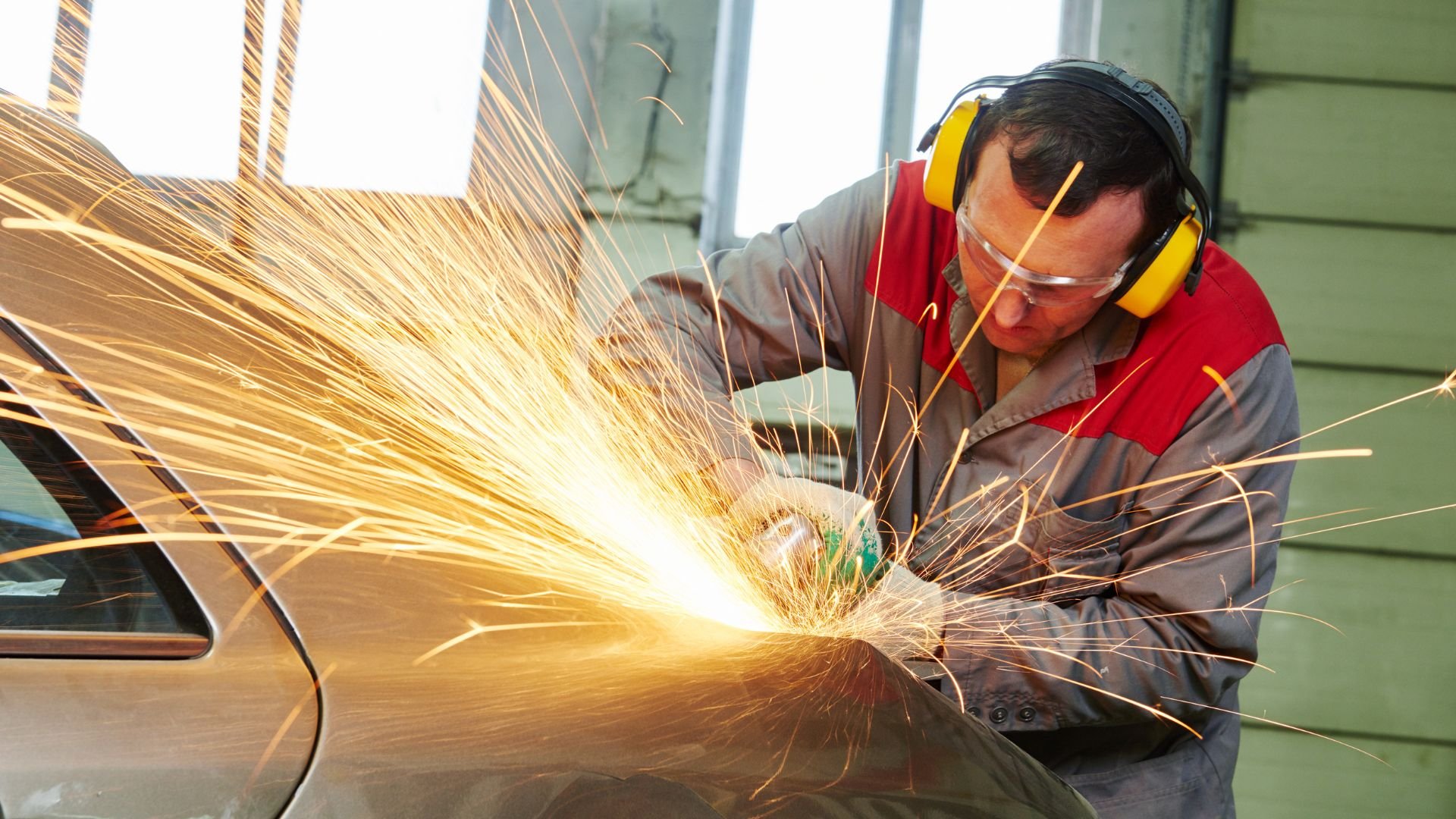Worker grinding metal with sparks flying, wearing safety gear