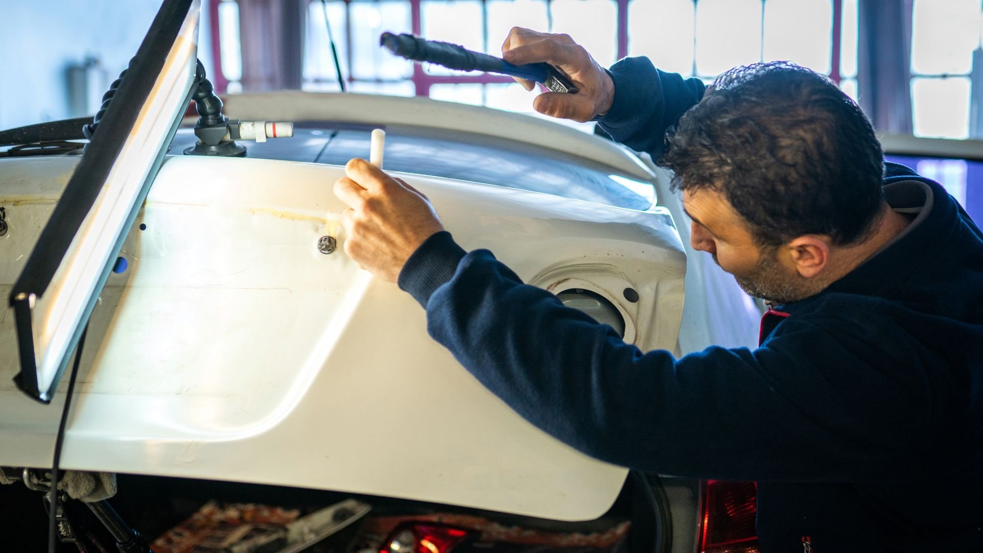 Mechanic working on vehicle body panel in auto repair shop