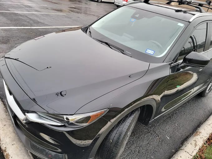 Black SUV with damage parked on wet asphalt in parking lot
