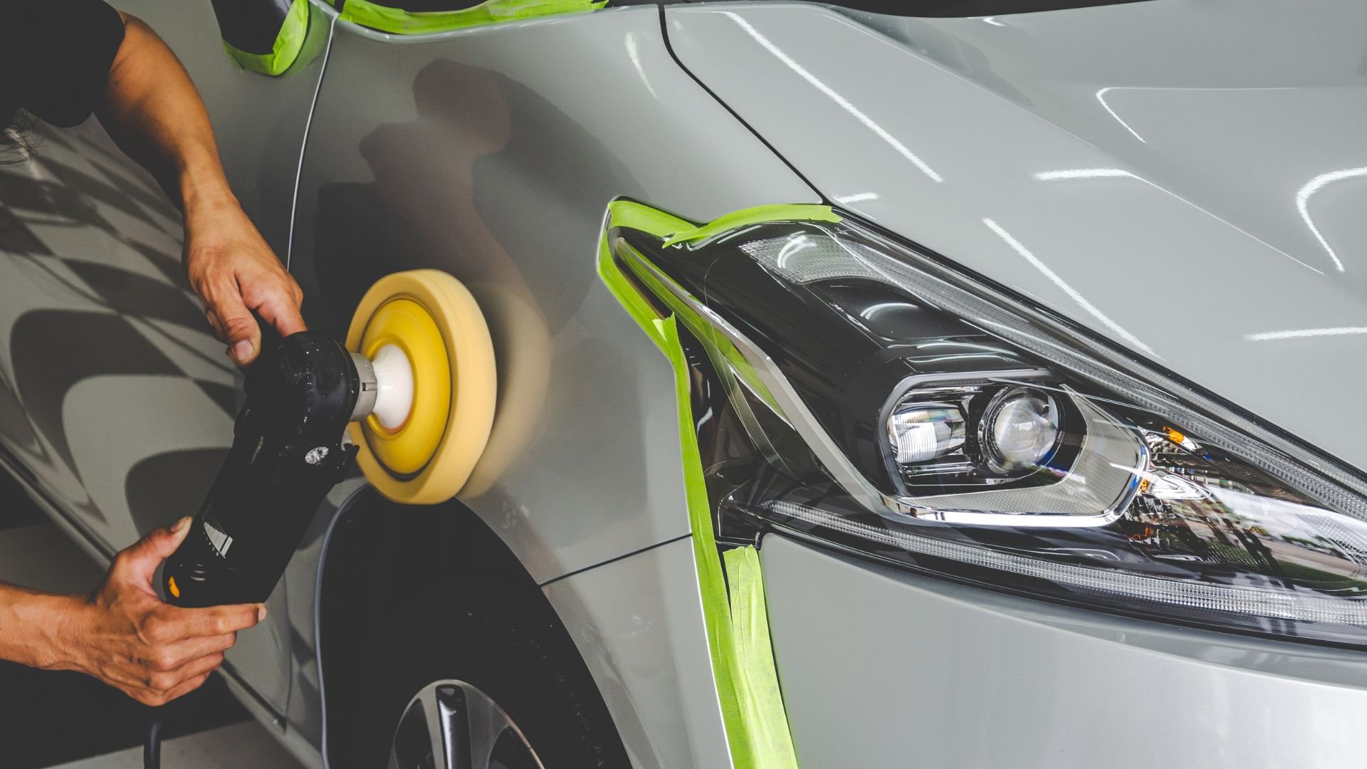 Car detailing with polishing machine on silver vehicle's sleek surface