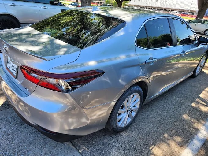 Silver Toyota Camry parked on street with trees casting shadows
