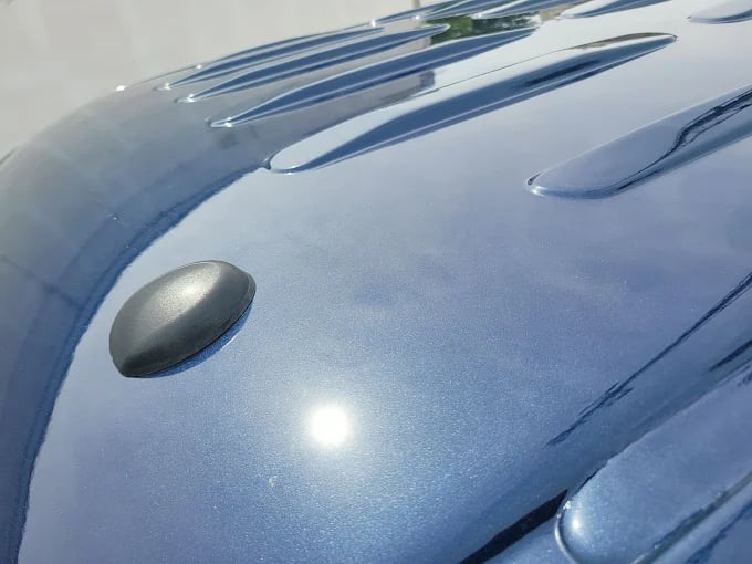 Metallic blue car hood with curved lines and reflective surface