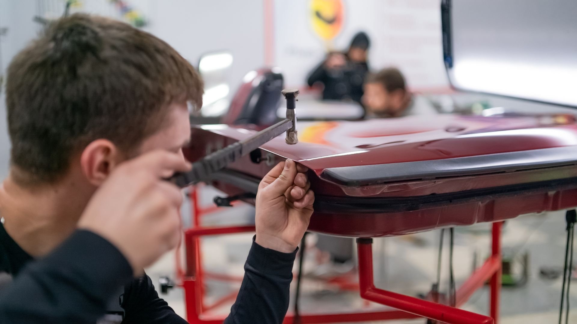 Technician repairing car body using specialized dent removal tool
